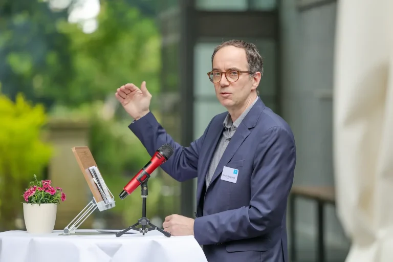 Marcel Weigand moderiert Charité Veranstaltung Digi Care 2030 Marcel Weigand steht auf einer Bühne und moderiert.