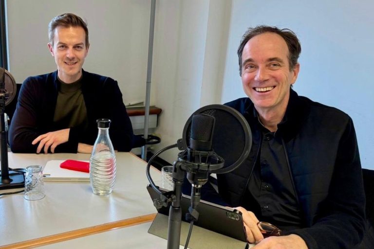 Marcel Weigand steht auf einer Bühne und moderiert.