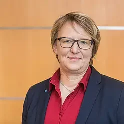 Foto von Prof. Dr. Sylvia Thun neben Testimonial zur Moderation von Marcel Weigand Prof. Dr. Sylvia Thun, in einem roten Hemd und dunklem Blazer.